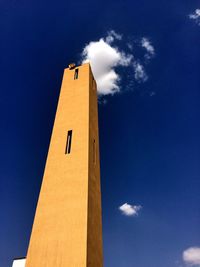 Low angle view of yellow tower against blue sky