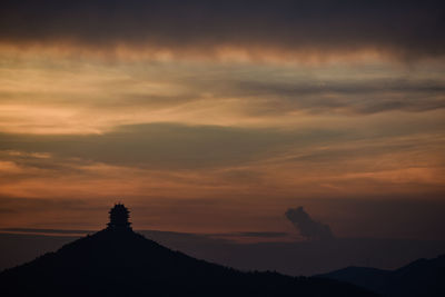 Silhouette mountain against dramatic sky during sunset