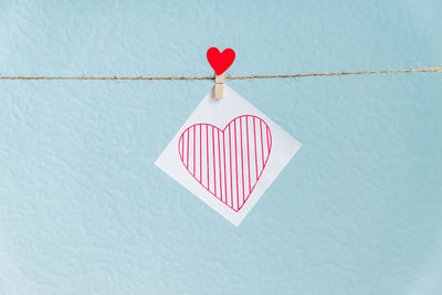 Close-up of red heart shape hanging on paper