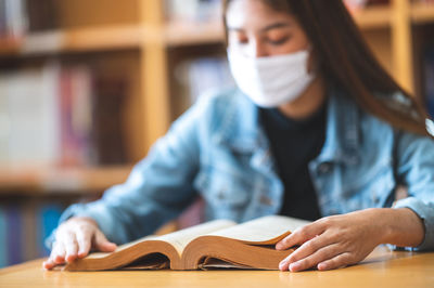 Young woman reading book on table