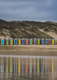 Multi colored chairs by river against sky