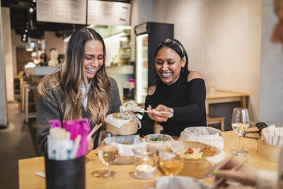 Happy young woman holding ice cream in restaurant