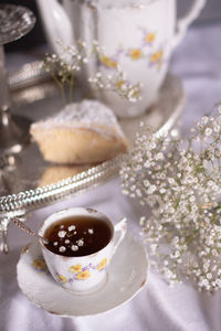 White still life with cheesecake and gypsophila and cup of tea, light and airy