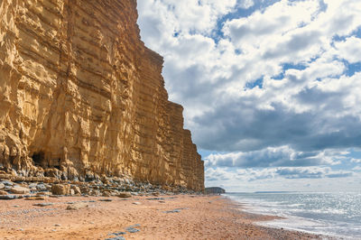 Rock formation on beach against sky