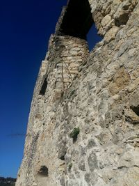 Low angle view of rock against clear blue sky