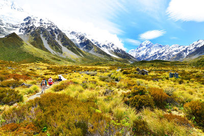 Hikers walking on road amidst field against sky