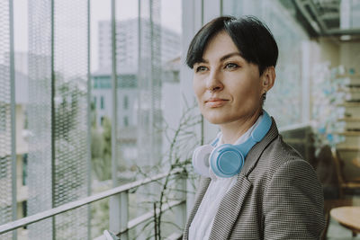 Thoughtful businesswoman with short hair wearing wireless headphones