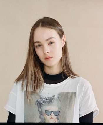 PORTRAIT OF SMILING YOUNG WOMAN AGAINST WALL