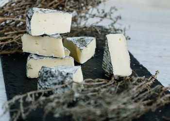 Cheese slices amidst herbs on cutting board in kitchen