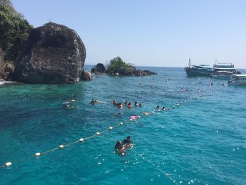 People swimming in sea against clear sky