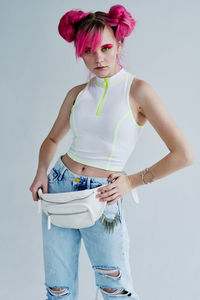 Portrait of young woman standing against white background