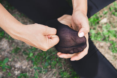 Woman sitting on grass and massages the foot in sock close-up. pain or cramping in the foot