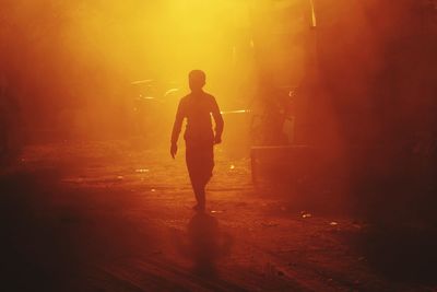 Silhouette man walking on road at night