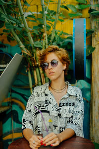 Portrait of young woman looking away while sitting outdoors