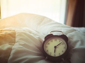 Close-up of alarm clock on bed at home