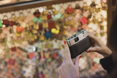 Close-up of hand holding camera against glass ceiling