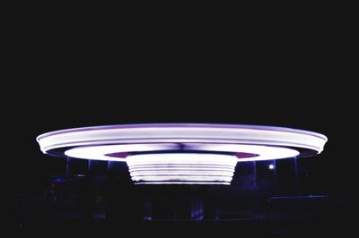 Low angle view of illuminated carousel against clear sky at night