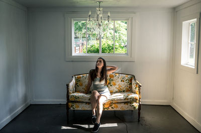 Full length portrait of woman sitting at home