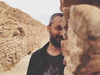 Portrait of man standing amidst old walls at desert