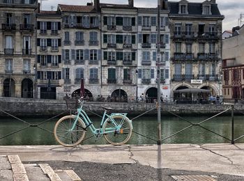 Bicycle by canal against buildings in city