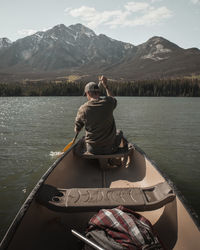 Rear view of man paddling boat in lake