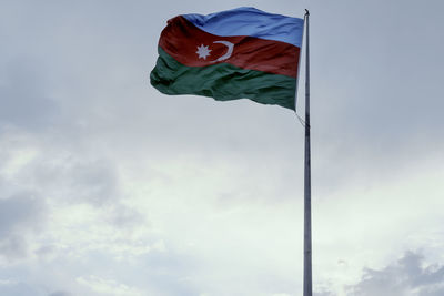 Low angle view of flag waving against sky