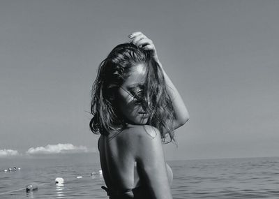 Full length of shirtless girl standing at beach against sky