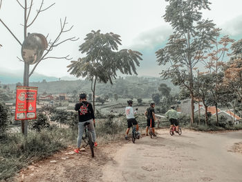 People on road by trees against sky