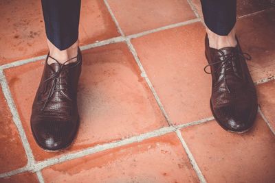 Low section of man wearing shoes while standing on footpath