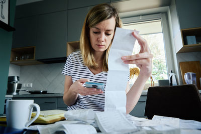 Woman calculating payment bill in kitchen