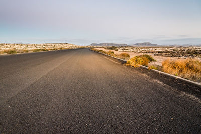 Empty road amidst land against sky