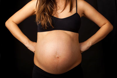 Midsection of woman standing against black background