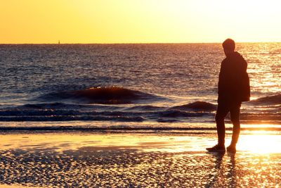 Full length of silhouette man standing on shore at beach during sunset
