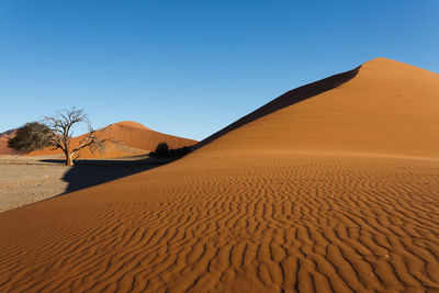 Sand dunes in desert against clear blue sky