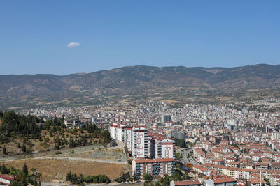 Aerial view of townscape and mountains against clear sky