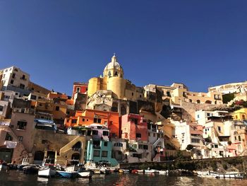 Low angle view of buildings in city against clear blue sky