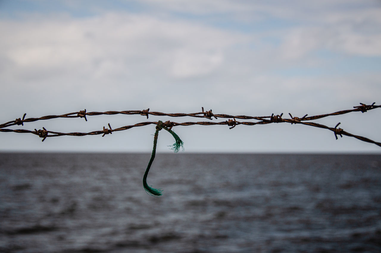 CLOSE-UP OF BARBED WIRE AGAINST SKY