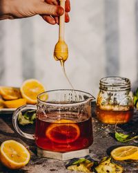 Close-up of hand holding dipper over honey in glass