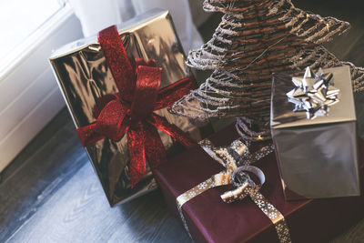 Gift boxes near christmas tree inside home. box with holiday ribbon with bows. festive atmosphere