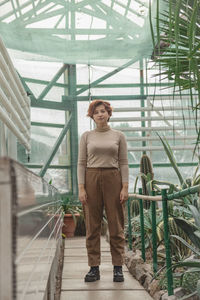 A beautiful plus size girl standing among the green plants of the greenhouse. cottagecore style