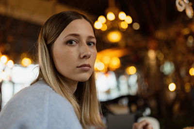 Portrait of woman sitting against illuminated light