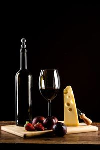 Glass of wine and glasses on table against black background