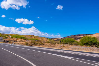 Road by land against blue sky