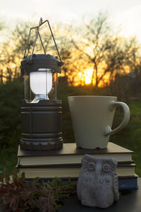 Close-up of coffee cup on table against sunset