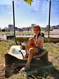 Happy woman sitting by fence