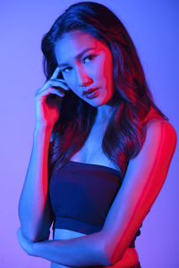 Portrait of beautiful young woman standing against blue background