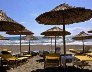 Lounge chairs and parasols on beach against sky