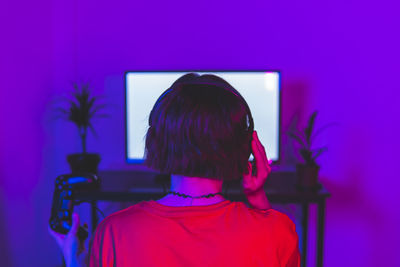 Woman adjusting headphones while playing video game at home