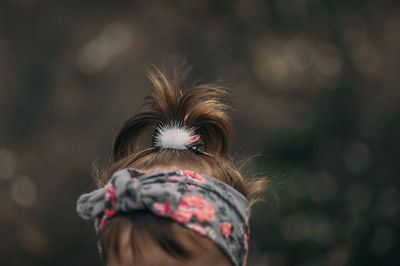 A girl with short dark hair, a fluffy white hairpin and a violet headband