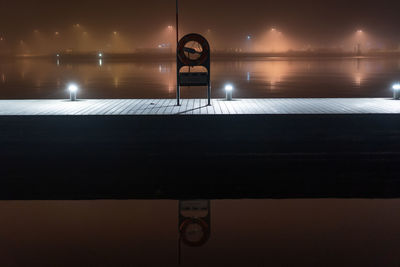 Reflection of illuminated light on mirror against wall at night